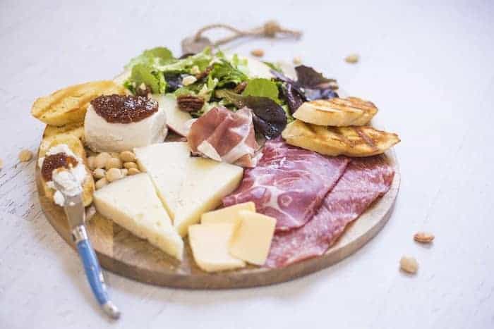 A charcuterie board with meat, cheese, and nuts.
