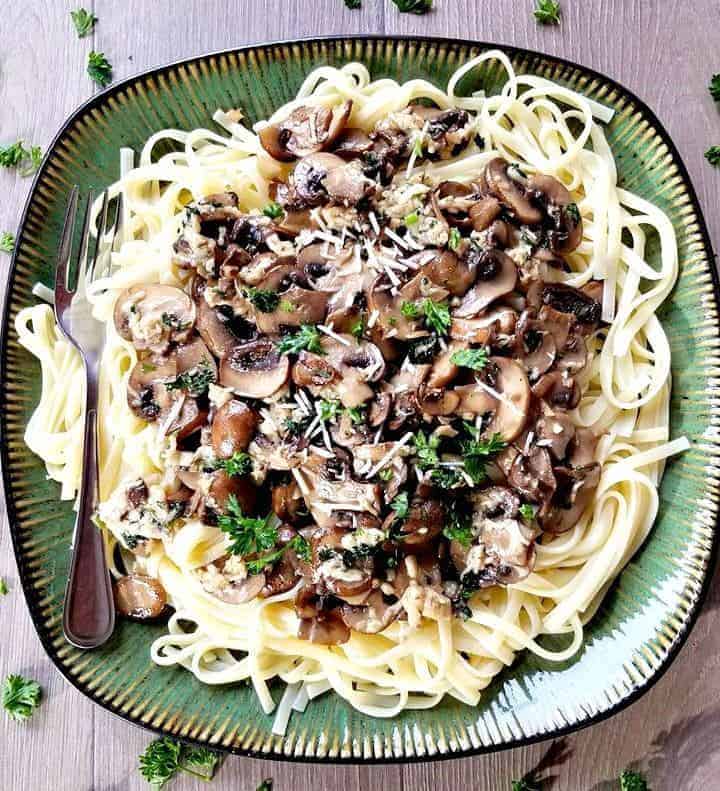 A plate of food with pasta, mushrooms, and a fork.