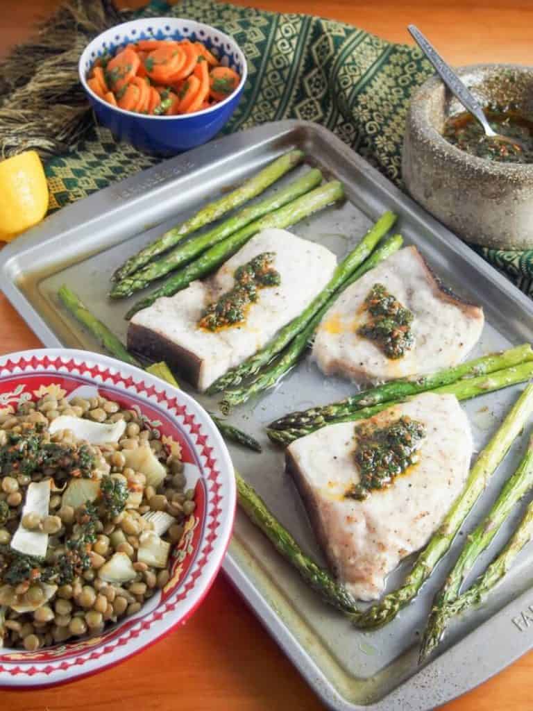 A pan has asparagus and meat laid out on it.