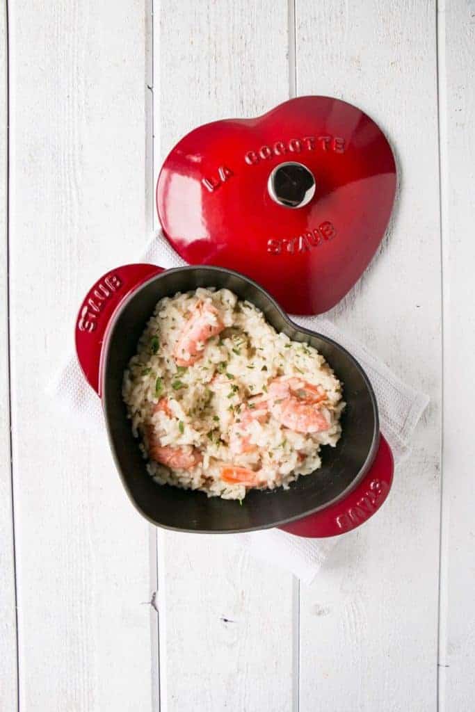 Grains with shrimp inside a red heart-shaped pot.