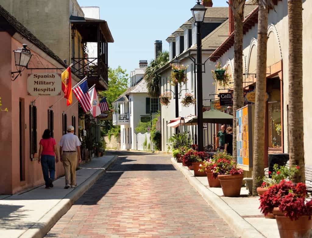 People walk down a street lined with shops.