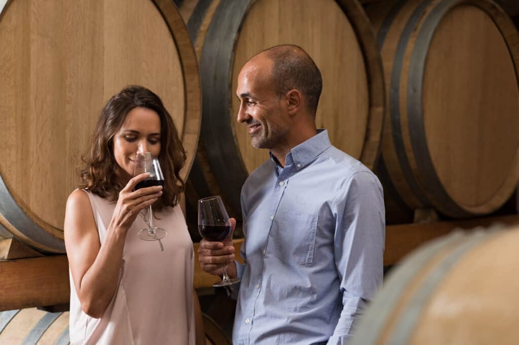 A couple smiles while holding a glass of wine.