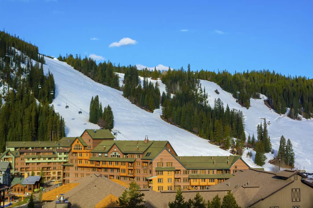 View of a ski resort with ski slopes behind.