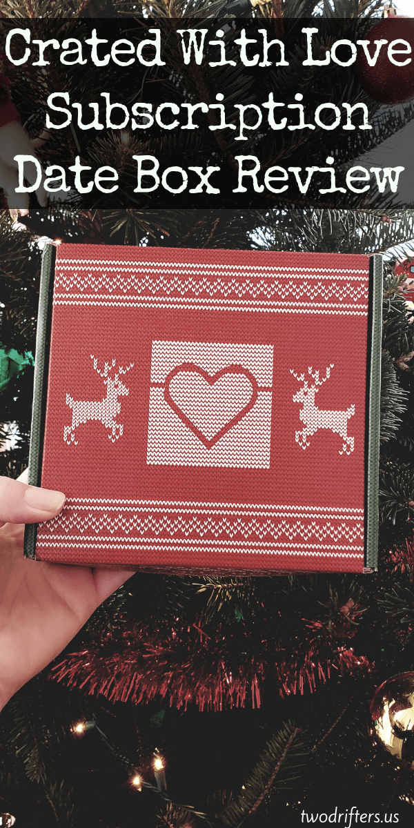 A person holding a red box with a Christmas tree behind.