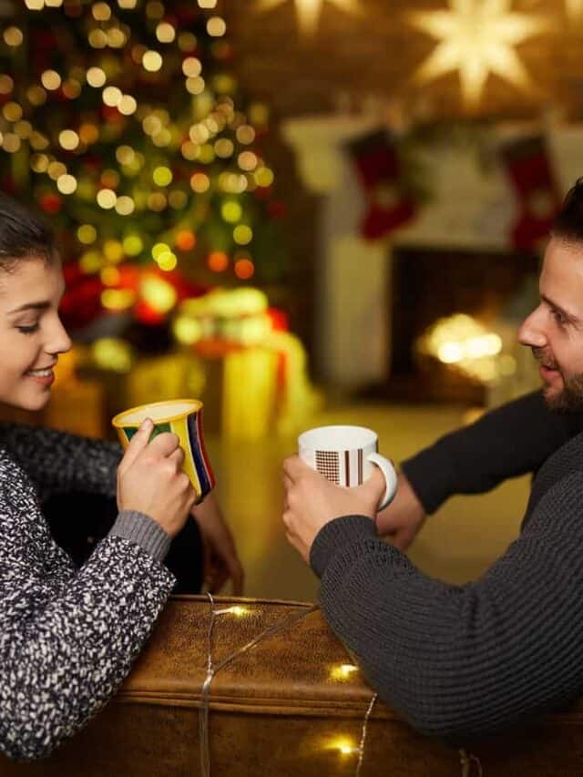 A man and Woman sitting on a bench together holding coffee mugs.