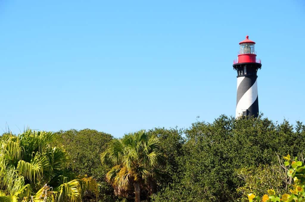 A black and white striped lighthouse sticks out above trees.