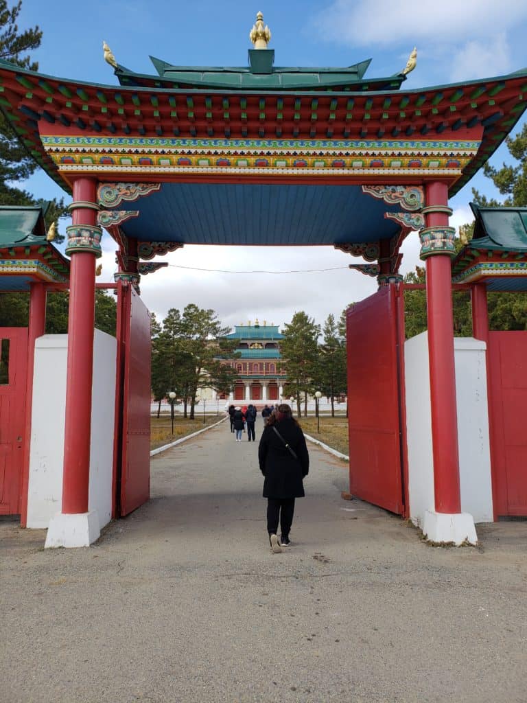 A person walks under a unique red pagoda.