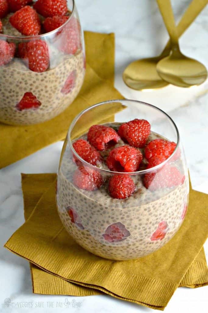 Chia pudding in a glass with raspberries on top.