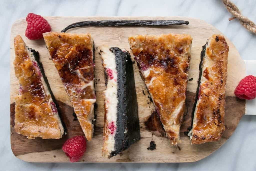 Slices of cheesecake are on a wooden board.
