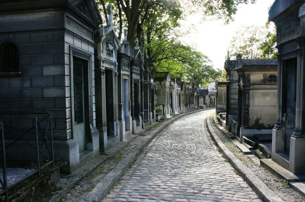 An empty cobblestone street leads through crypts.