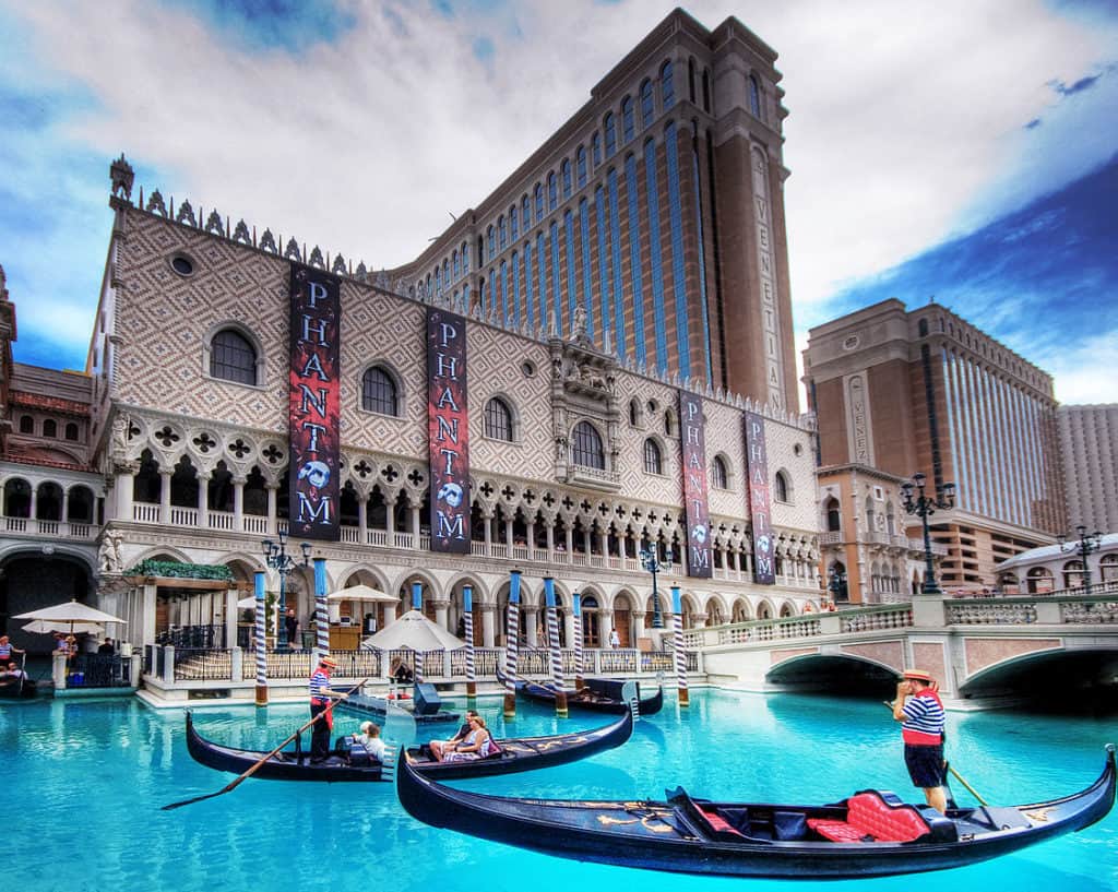 Gondolas float in water in front of a hotel.