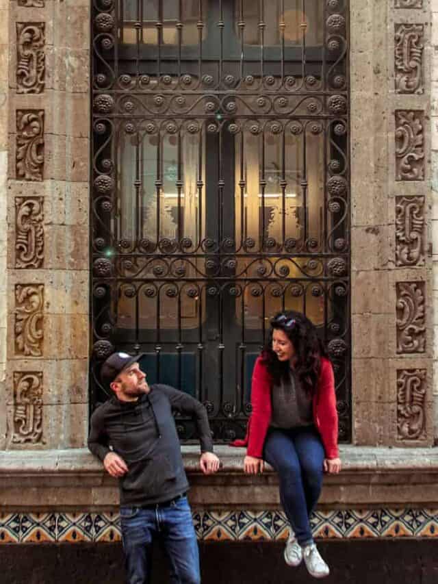 A couple sits in front of a doorway with mosaic tiles.