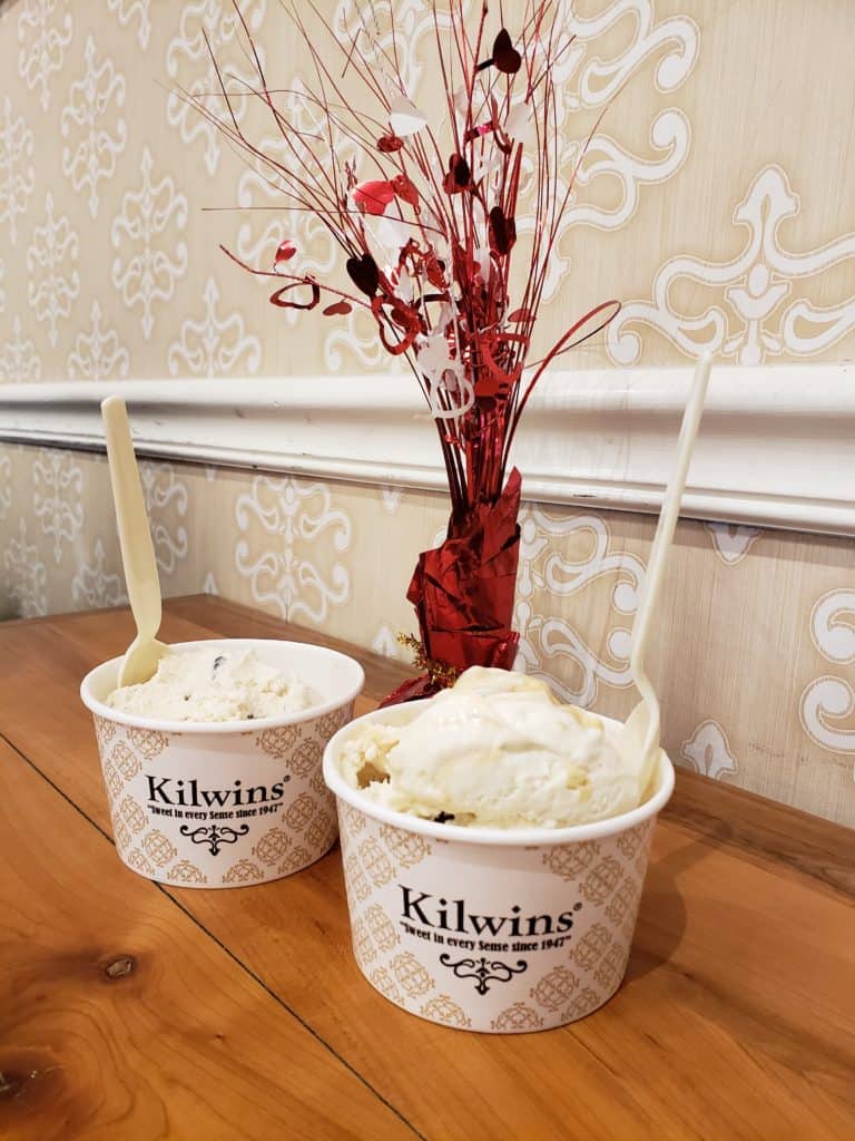 Two cups of ice cream in cups that say \"Kilwins.\"