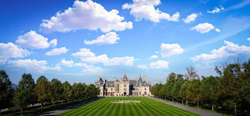 A historic building with a clean lawn in front surrounded by trees.