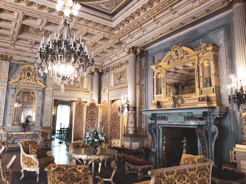 An elegant room with a fireplace and seating area with a chandelier.