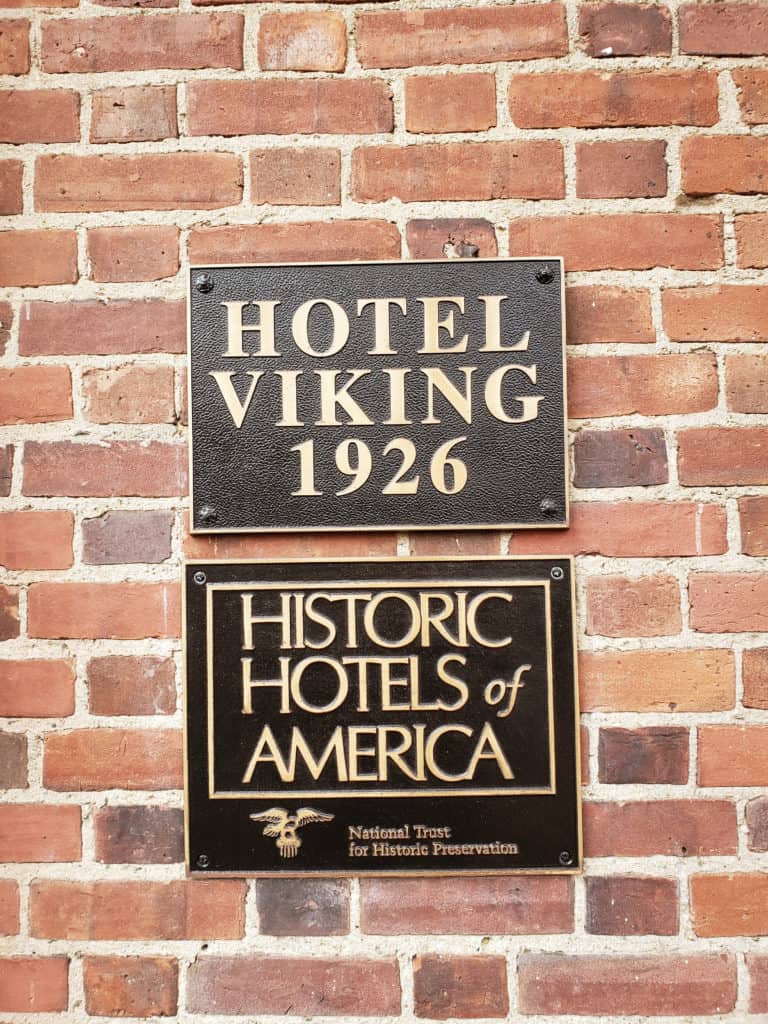 A black sign on a brick wall says Hotel Viking 1926. One underneath says Historic Hotels of America.