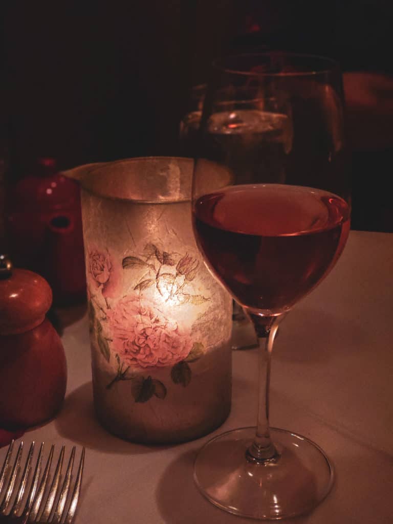A close up of a wine glass sitting on a table next to a candle.