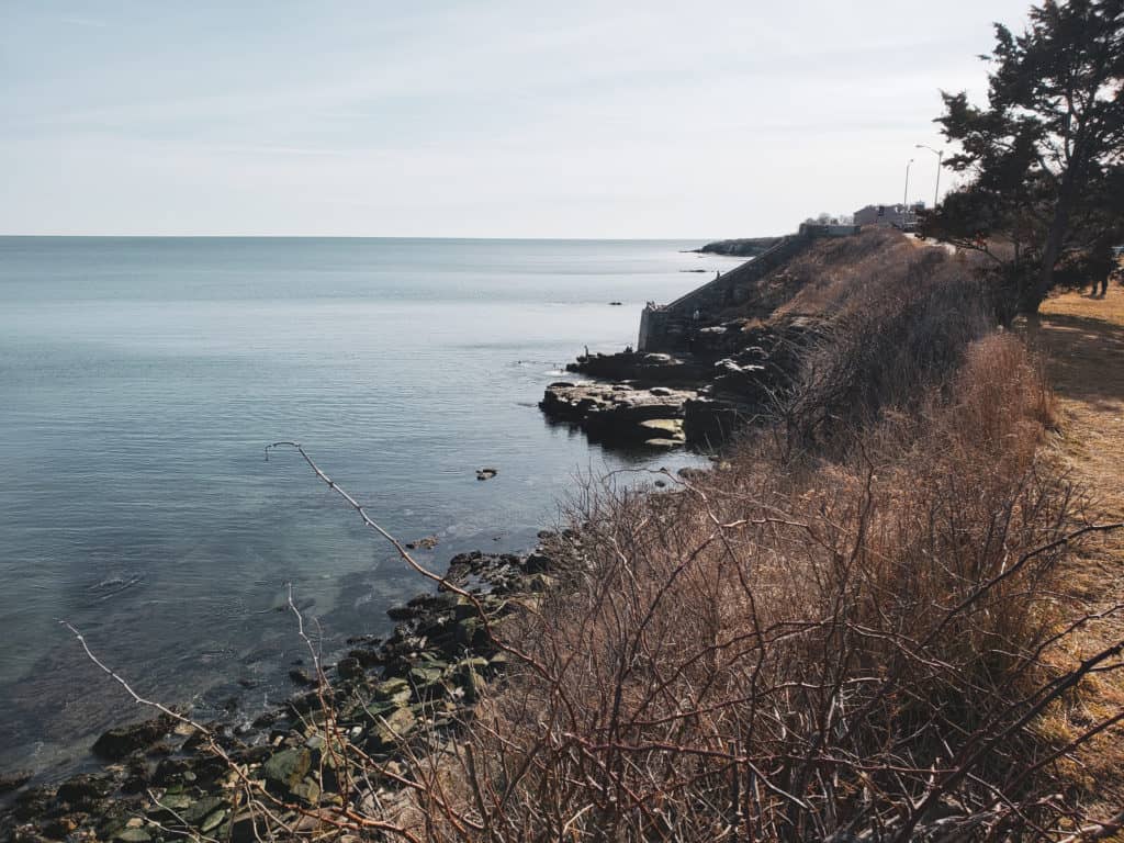 A blue body of water with a cliff beside it.