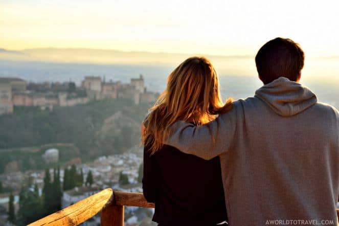 A couple looks out over a scenic vista of a village and mountains in a romantic European destination