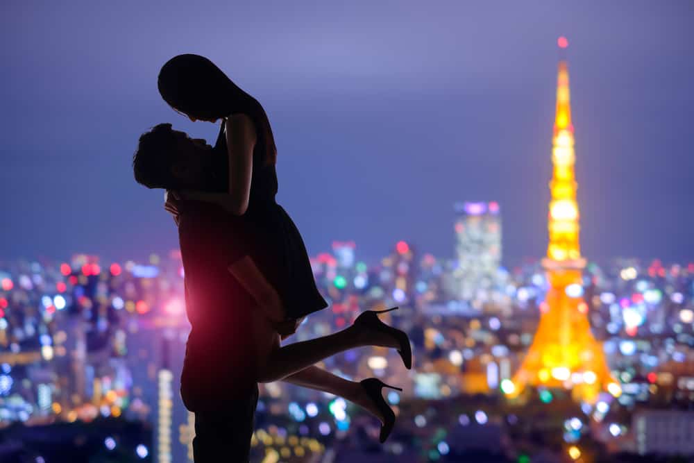 Silhouette of romantic lovers with the Tokyo Tower behind at sunset.