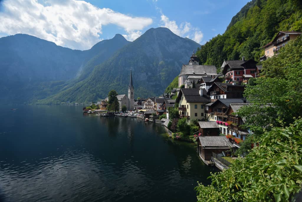 A beautiful mountain village is seen under blue skies with a lake on one side and the village ensconced in the mountains on the other