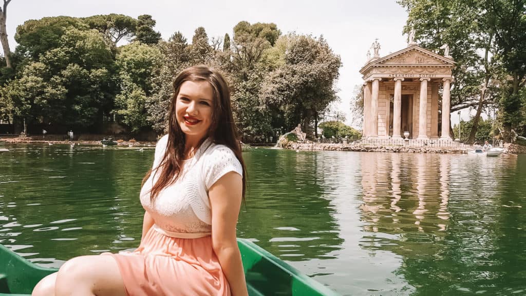 A woman sits in a canoe on water in a romantic honeymoon spot in Europe