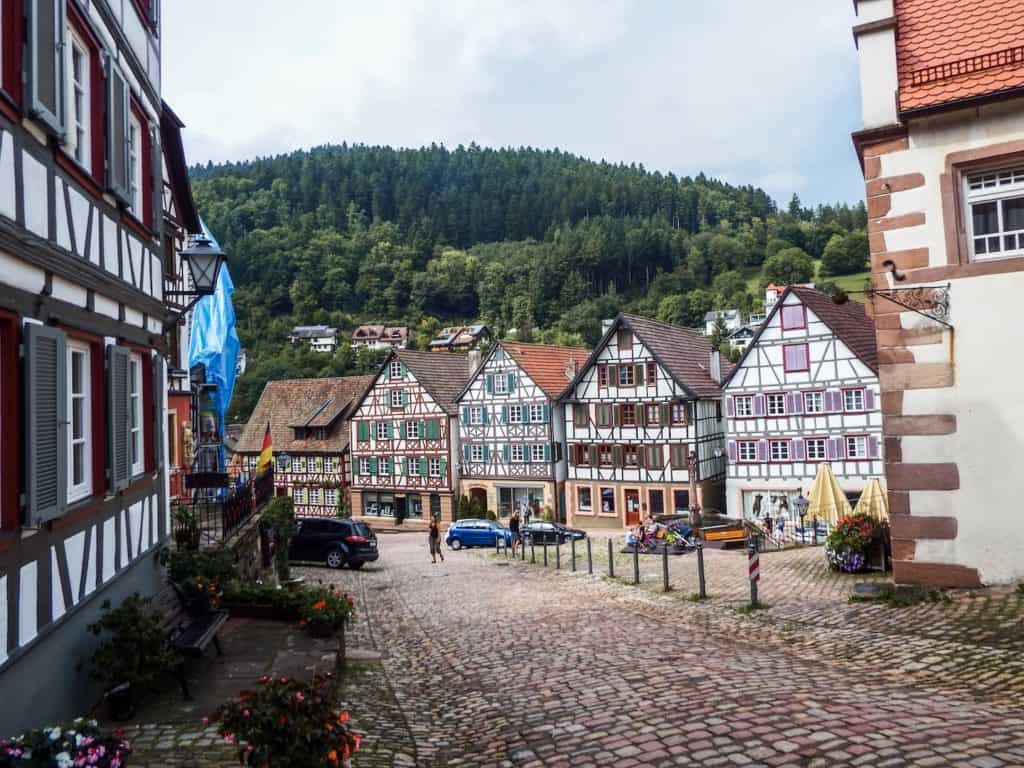 A small brick road leading down a hill that has old storybook styled houses on either side. 