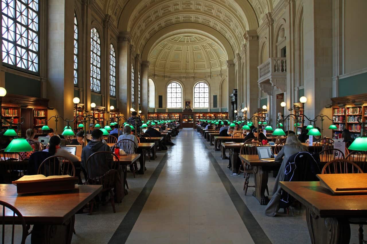 People working inside a library with green lamps.