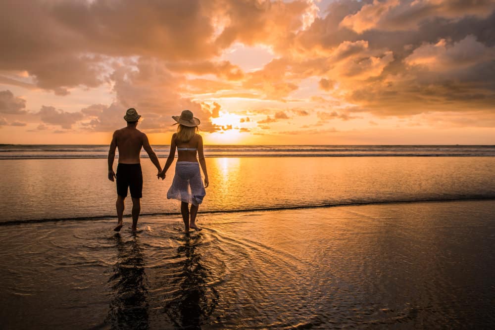 couple holding hands on a beach during sunset - a romantic scene for a honeymoon in south america
