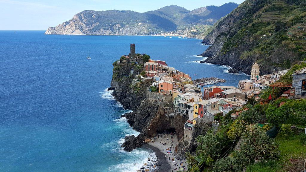 A narrow cliffside jutting out into the water with colorful buildings along the top. 