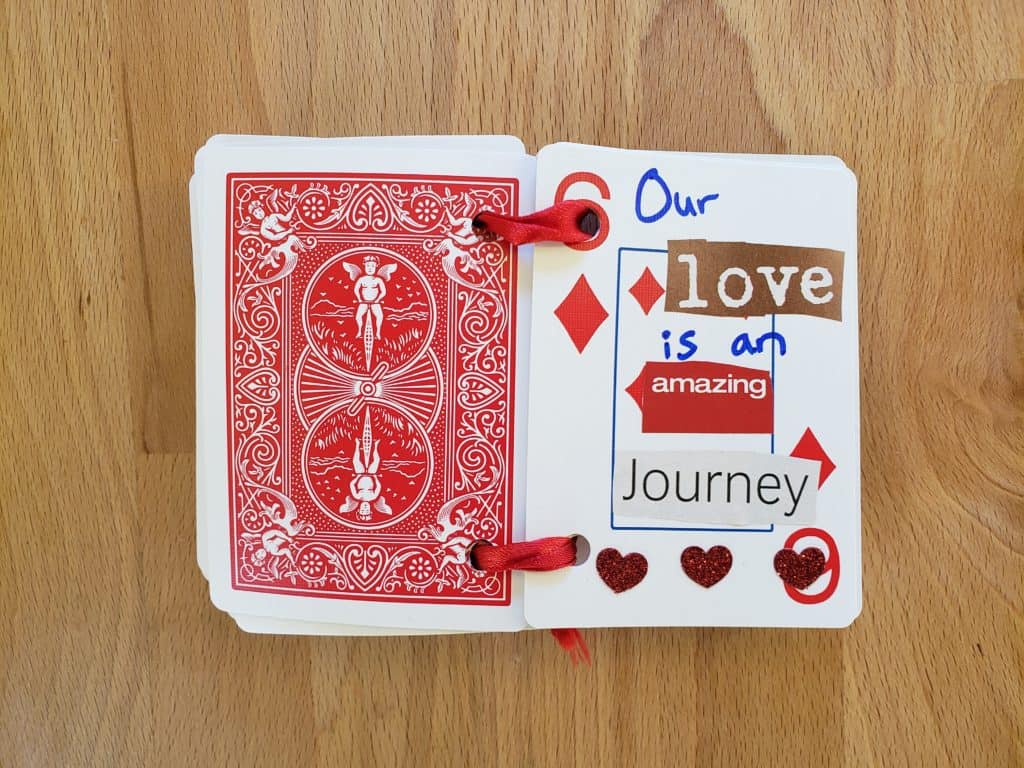 A set of cards is open to a 6 of Diamonds that says Our love is an amazing journey.