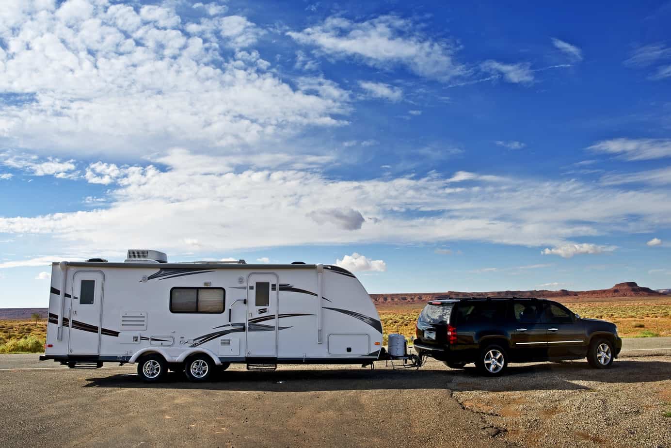 A travel trailer being pulled by an SUV in the desert.