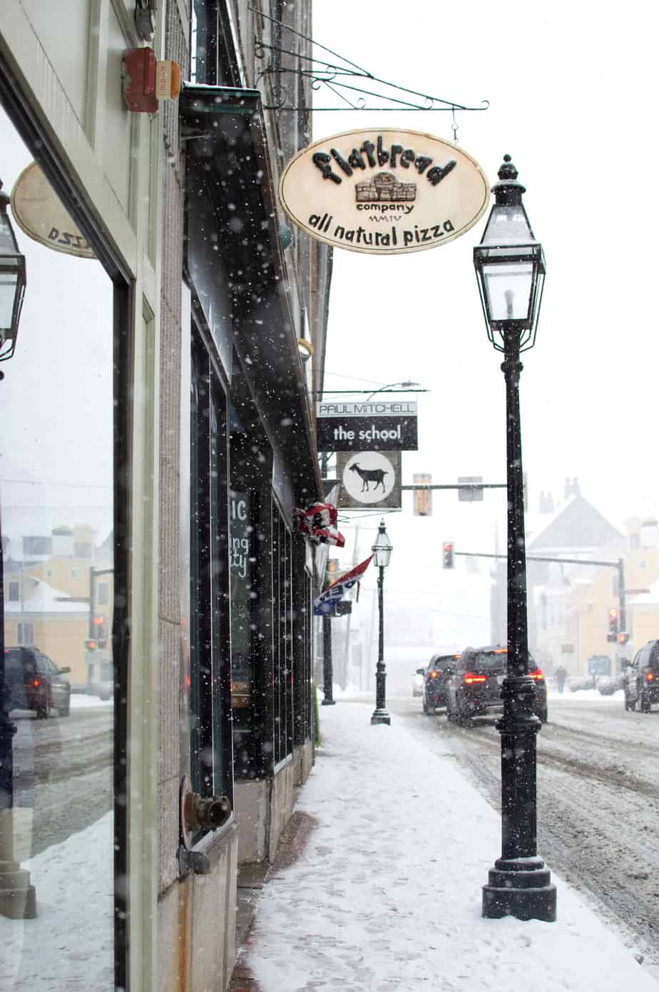 A snowy sidewalk with street lights in front of stores in Portsmouth New Hampshire