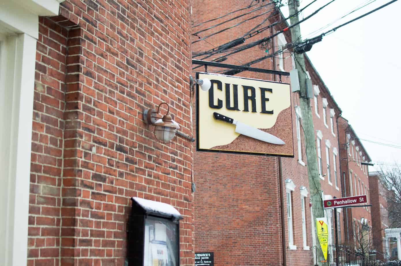 A sign on the exterior of a brick building that reads \"Cure\"
