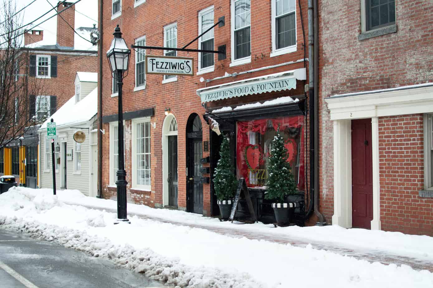 A row of stores with two potted trees out front