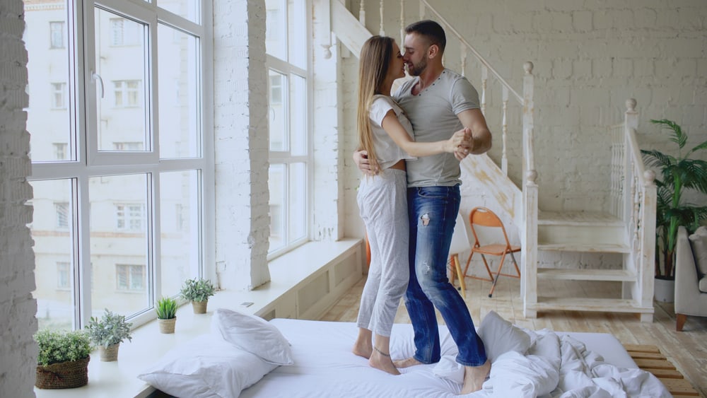 A man and woman are dancing on a bed.