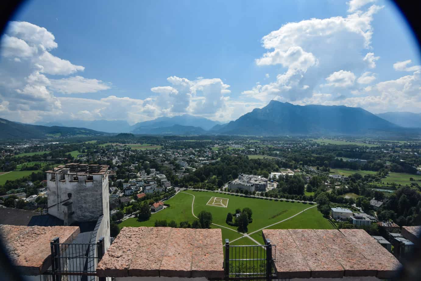 View of a town and a big green space with mountains in the background.