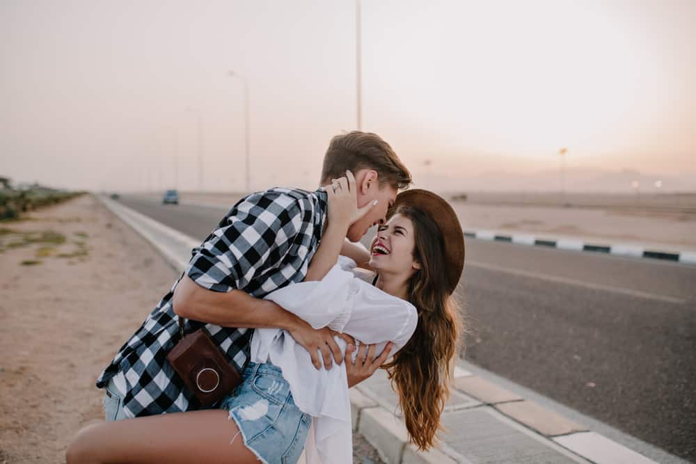 A couple dances in the desert sunset by a highway.