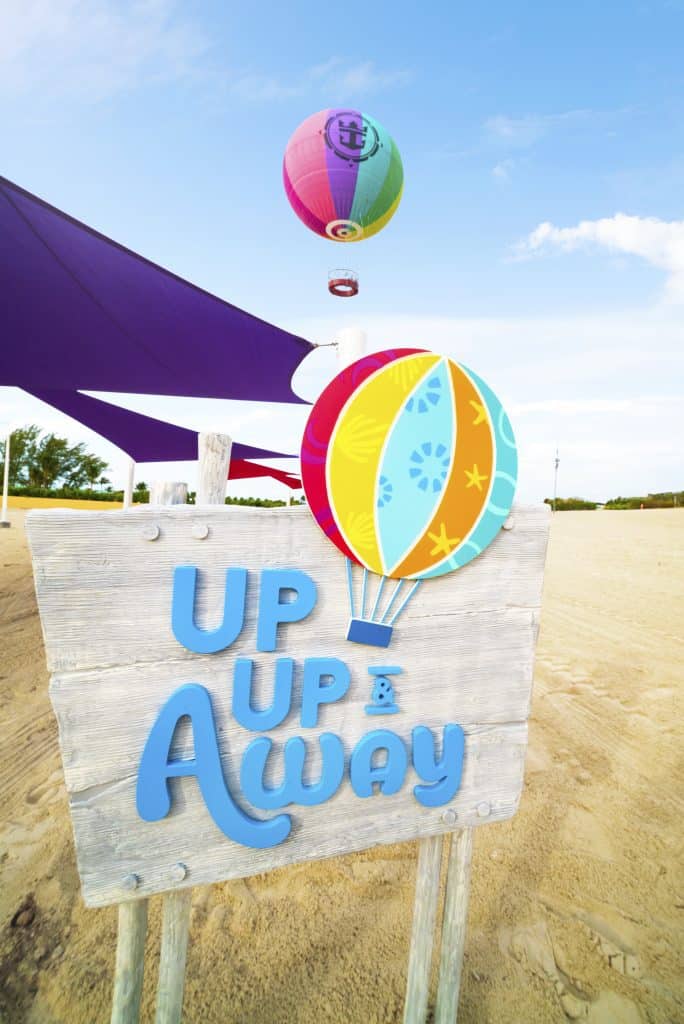 A sign that says \"Up Up & Away\" with a hot air balloon floating in the distance. 