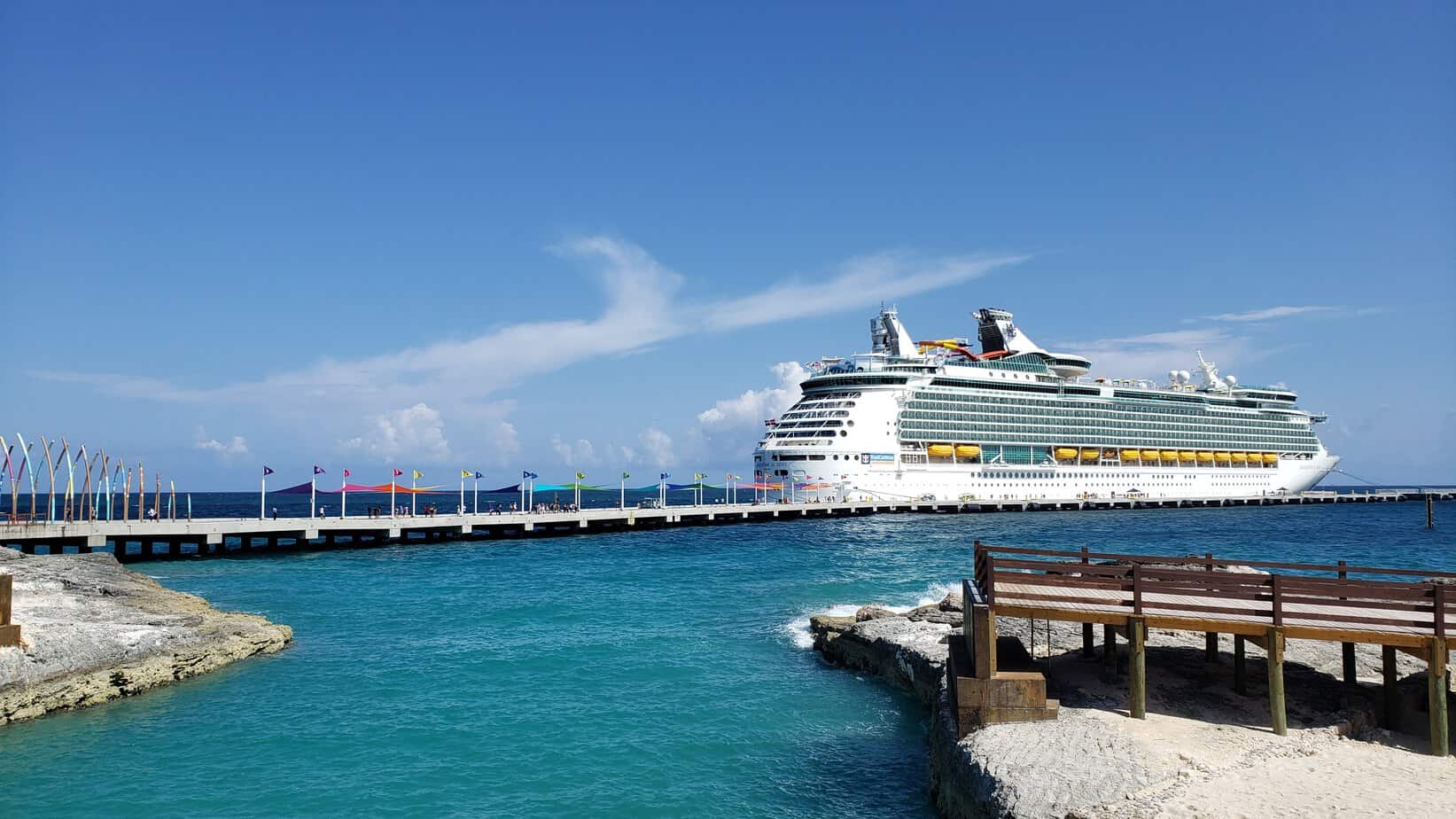 A white cruise ship is parked next to a dock.