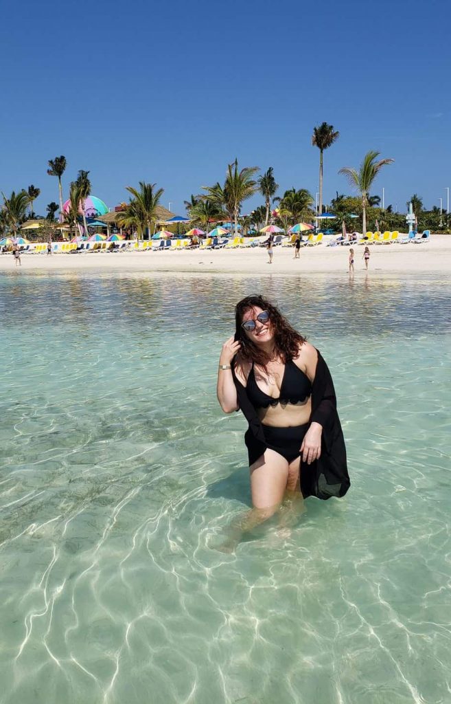 A woman standing in the ocean while smiling.