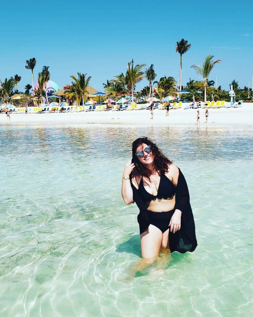 A woman in a black bathing suits miles in the ocean.