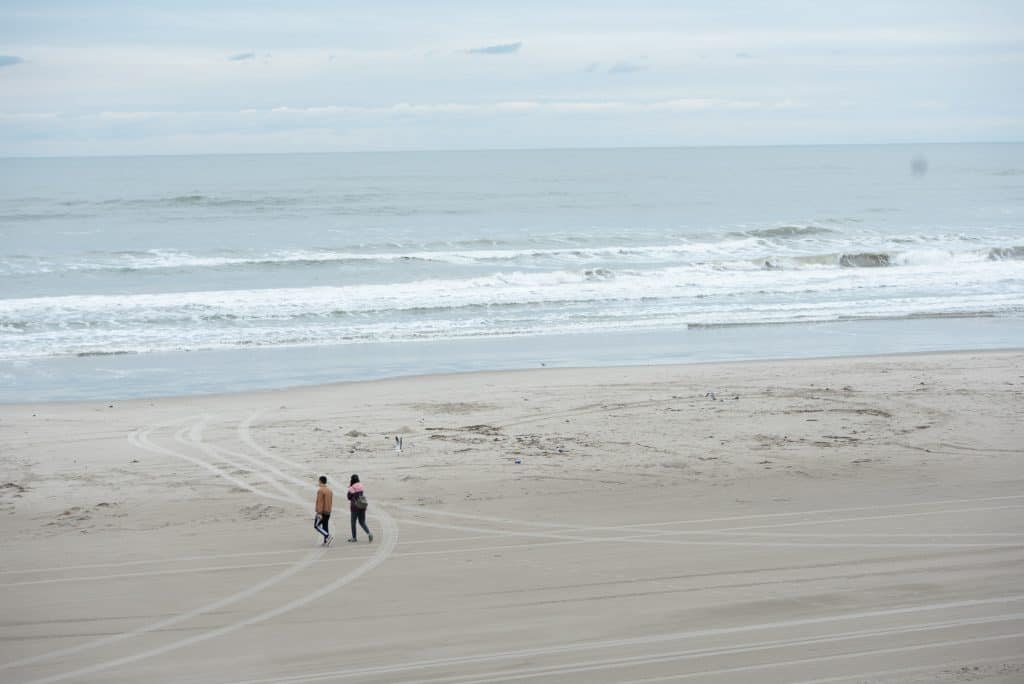 People walk on a clean sandy beach.