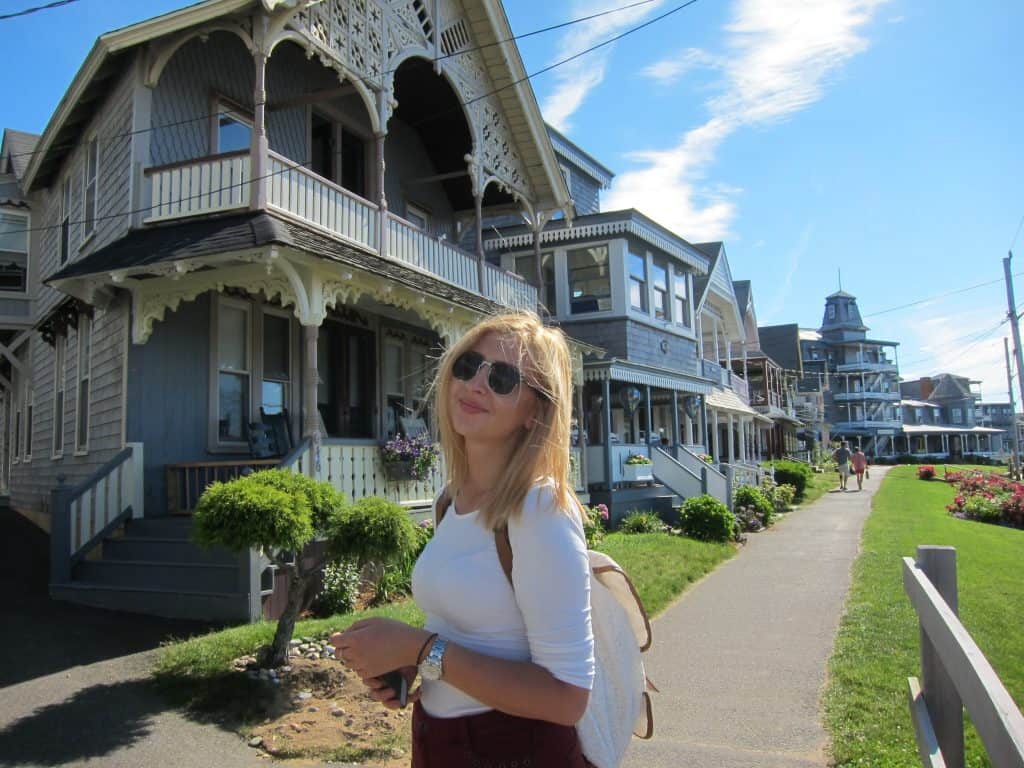 A woman smiles in front of historic Victorian homes.