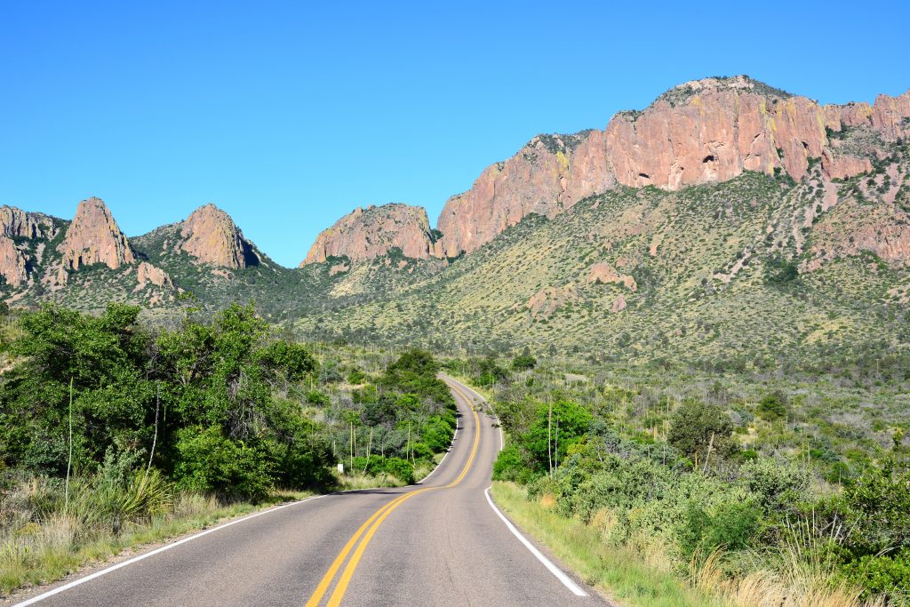 An empty road leads through a mountainous landscape.