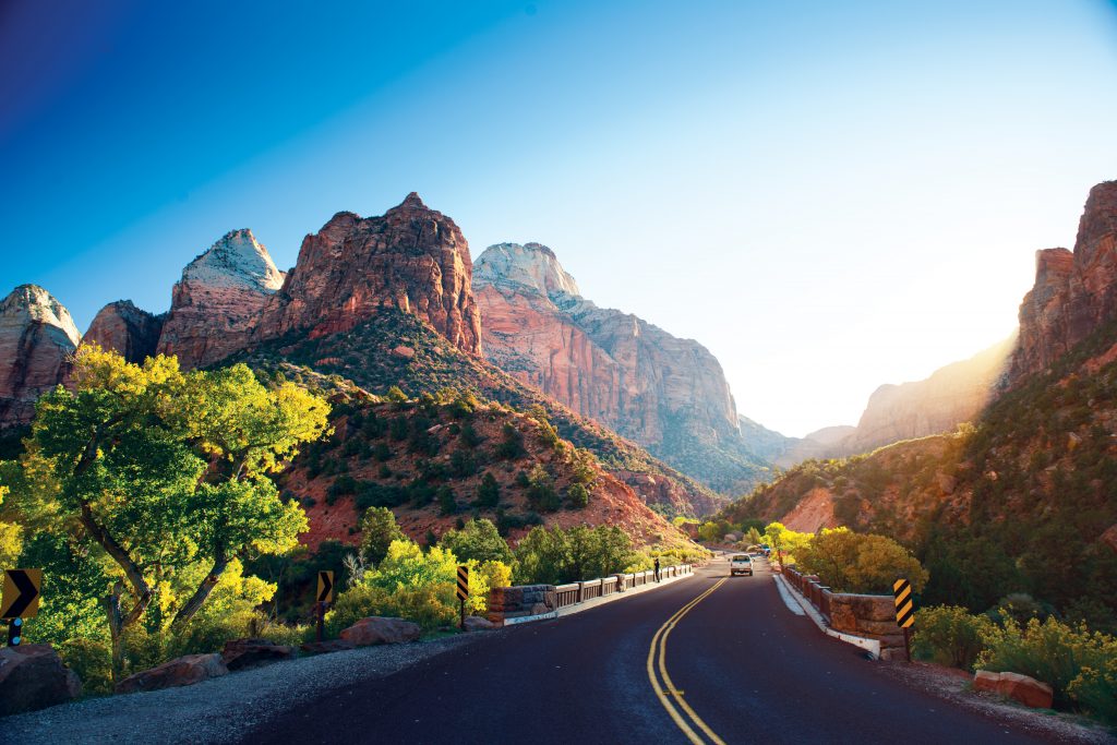 Cars drive on a road through a rocky landscape.