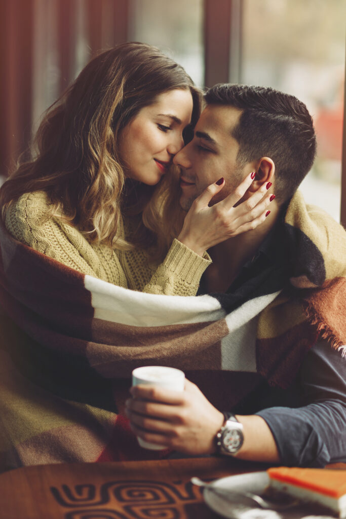 A couple in love kisses while the man holds a mug.