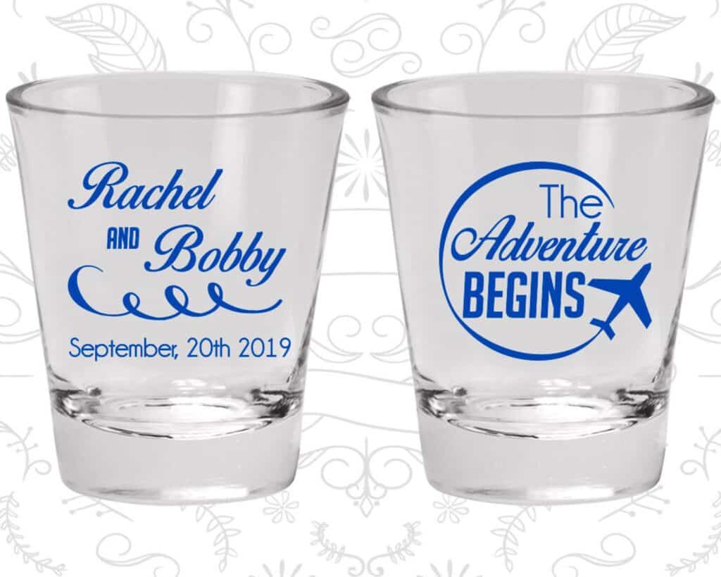 Clear shot glasses that say \"Rachel and Bobby September 20th 2019\" on one side and \"The Adventure Begins\" on the other in blue writing.