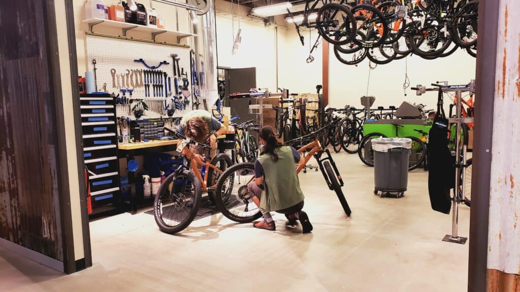 People standing around bikes in a bike shop.
