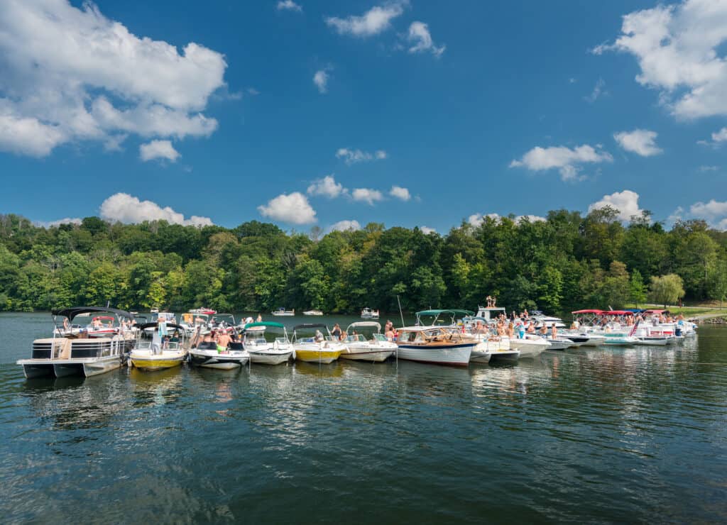 Boats are floating on the water surrounded by forest.